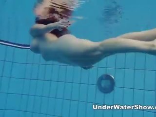 Redheaded nena nadando desnuda en la piscina